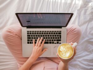 Freelancing woman working on laptop from home office with coffee and notebook